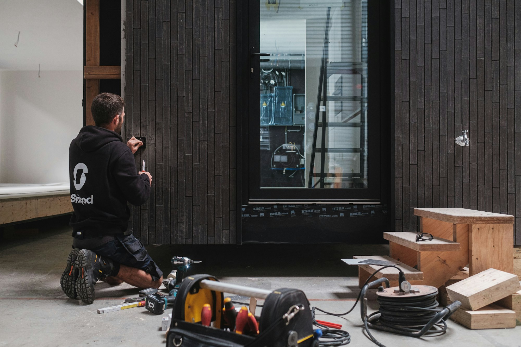 Elektricien aan het werk aan een houtskeletbouw module, prefab woningbouw