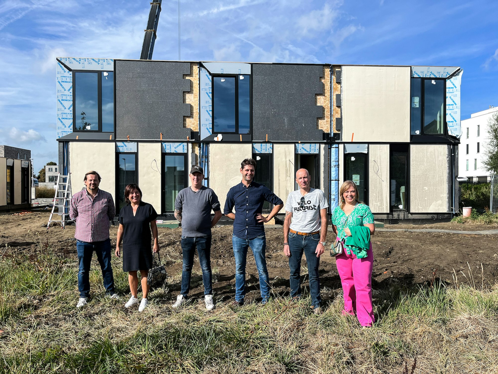 Groep van kopers en Skilpod team members staan voor de nieuwe Skilpod huizen op Hoedhaar in Lokeren